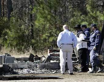 Пастор и представители властей осматривают пепелище сожженной церкви в Алабаме. Фото AFP, 8 февраля 2006 года 