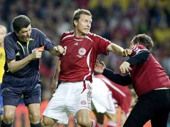 Игрок сборной Дании Микаэль Гравгаард (в центре) защищает Херберта Фанделя (слева) от болельщика.Фото AFP