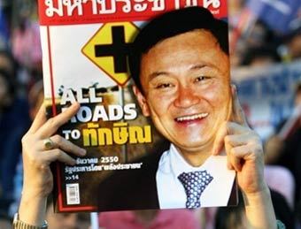 Участник предвыборного митинга в Бангкоке держит фотографию Таксина Чинавата. Фото AFP.